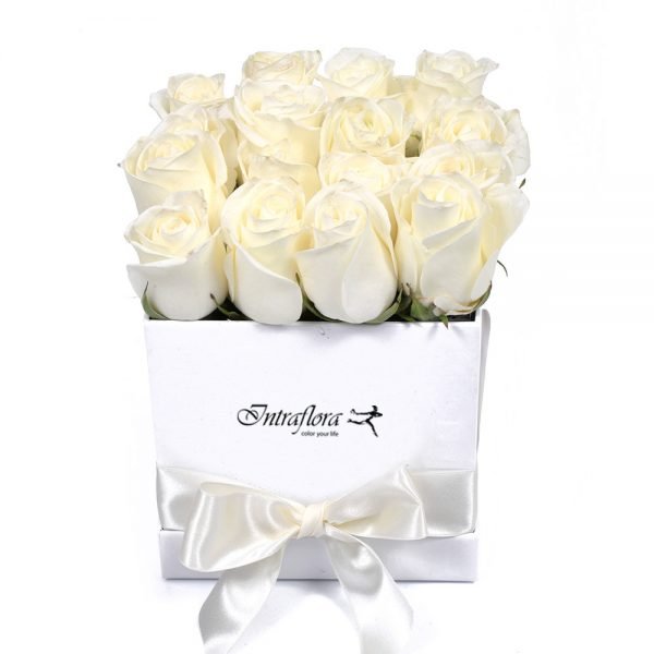 A square white box with the "Intraflora" logo, filled with white roses, decorated with a wide white ribbon and tied into a bow, against a white background.
