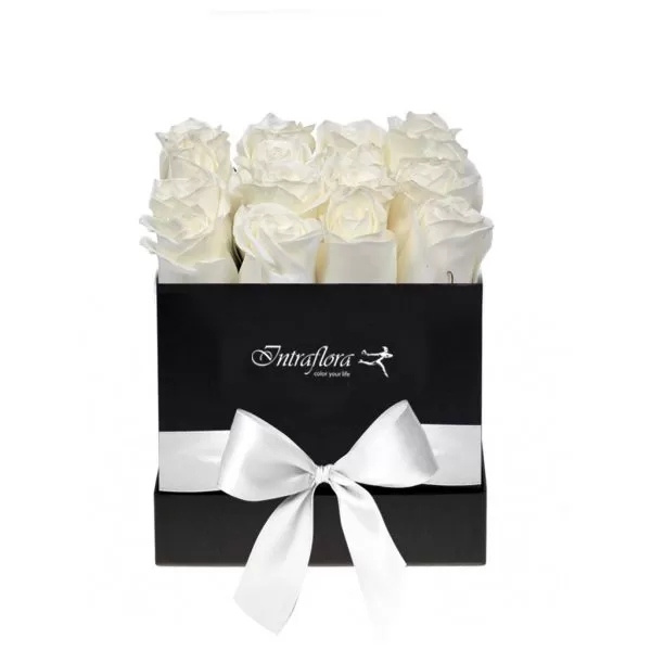 A black square box filled with white roses, decorated with a white ribbon and bow, against a white background. The box also features the "Intraflora" logo.