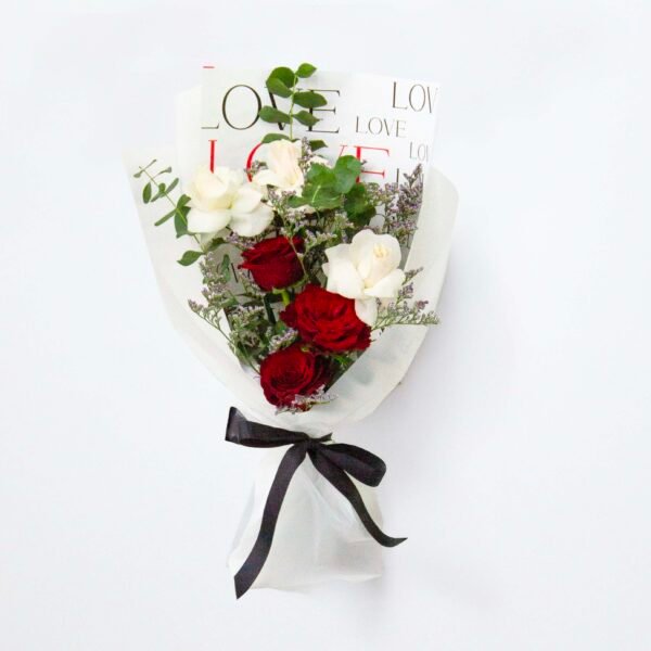 A bouquet of red and white roses wrapped in white paper with the word "LOVE" printed repeatedly, tied with a black ribbon, against a light background.