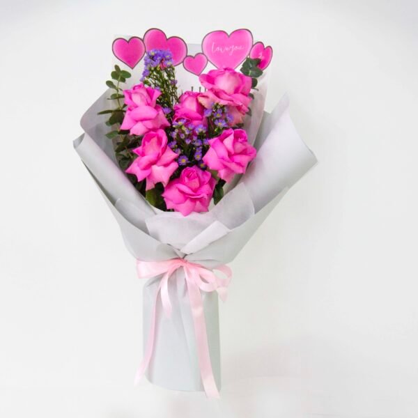 A bouquet of pink roses and purple flowers wrapped in light gray paper, tied with a light pink ribbon, with a small card featuring pink hearts and the phrase "For you," against a light background.